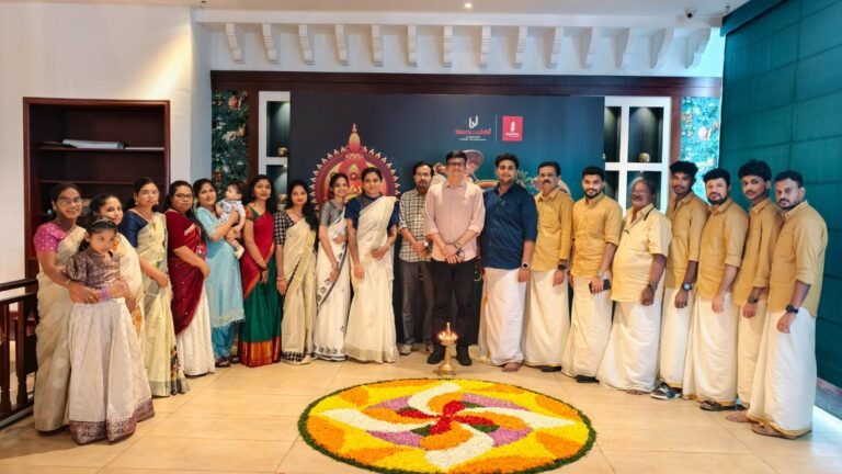 Group celebrating Onam in traditional Kerala attire with a colorful pookalam